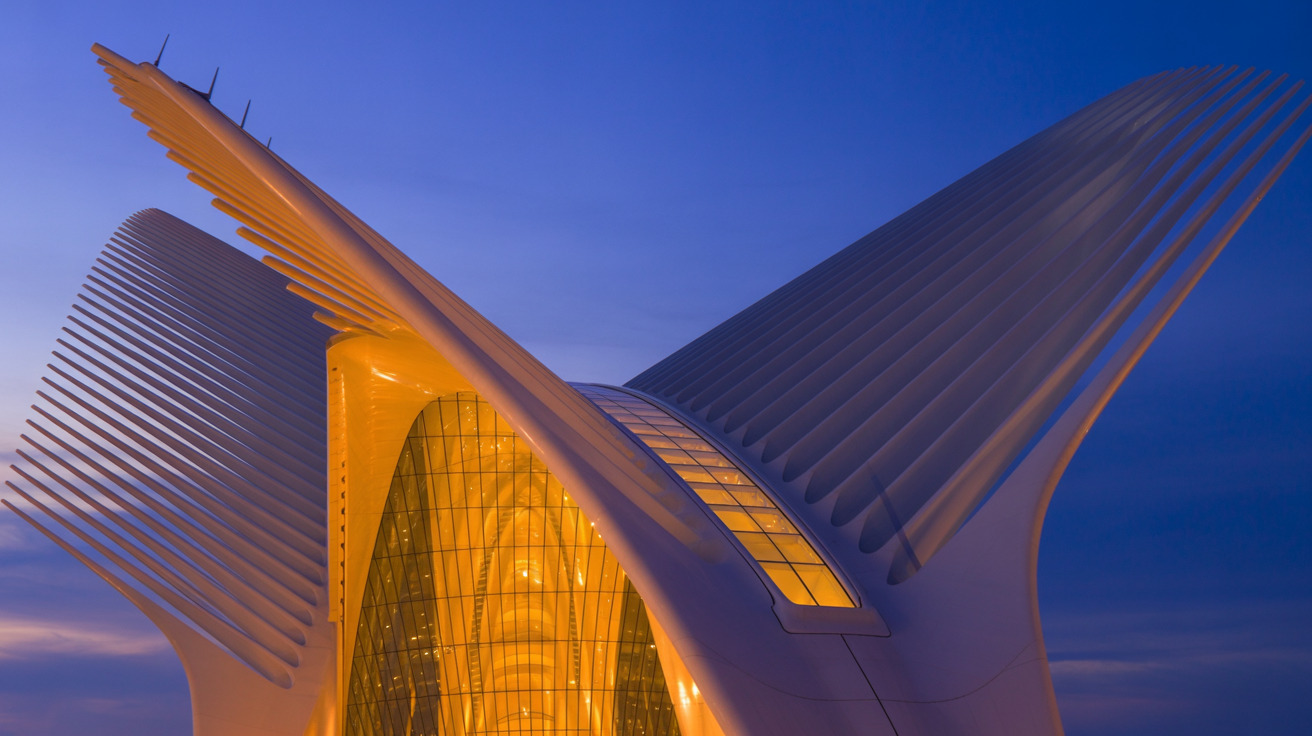 Calatrava-style white steel ribbed architecture glowing amber against twilight sky